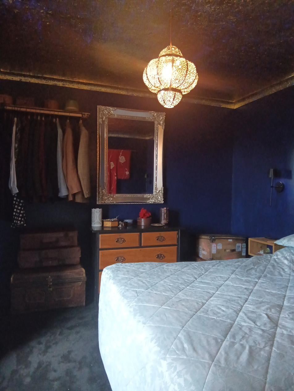 Bedroom with bed built from salvaged pews and gilded ceiling